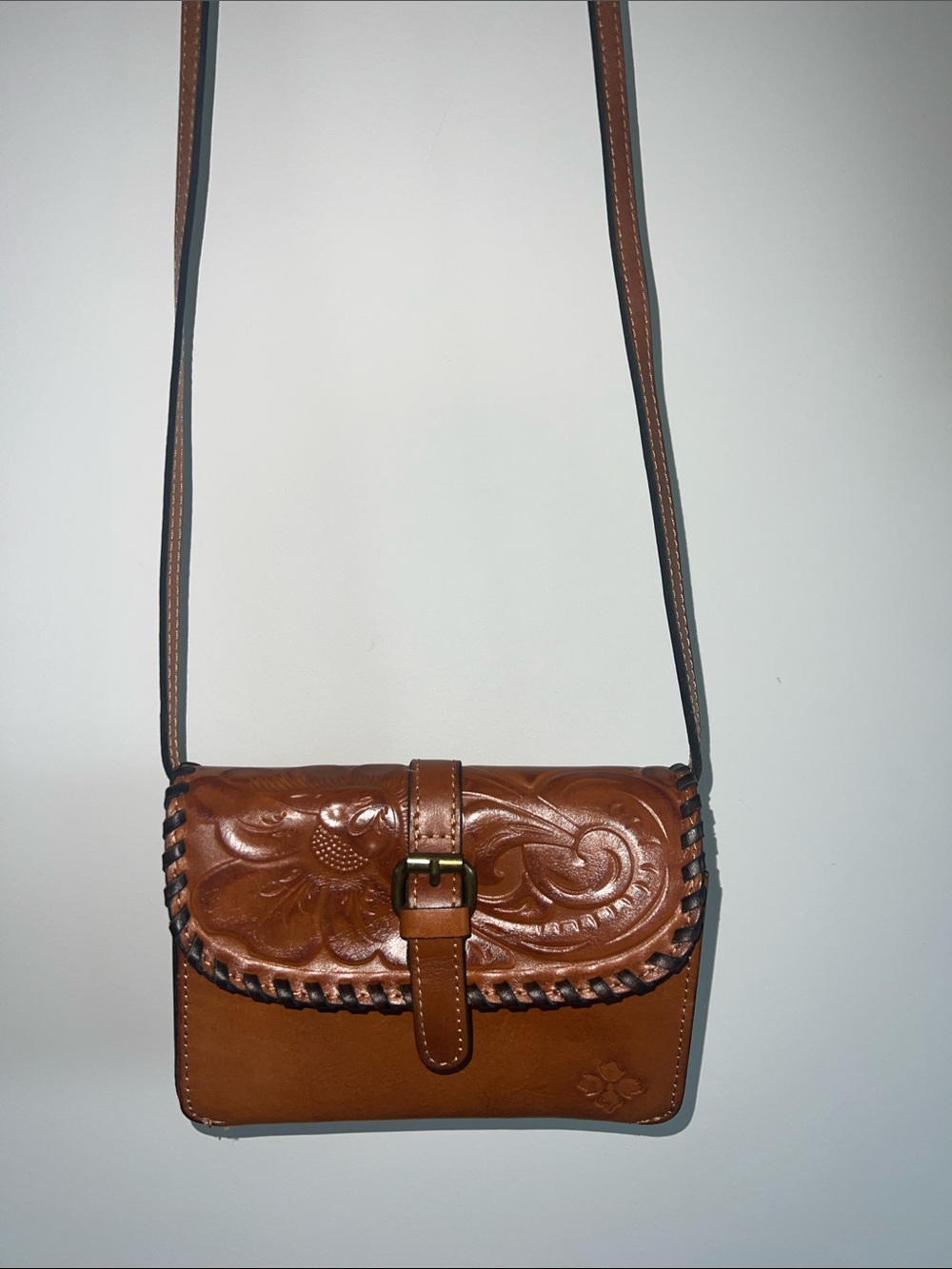 Patricia Nash Torri crossbody bag in cognac-brown tooled leather.